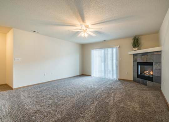 A living room with a fireplace and a ceiling fan.