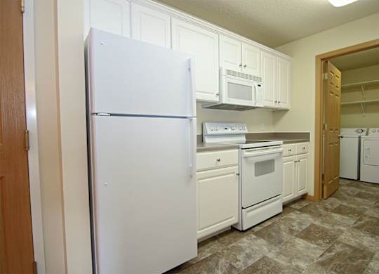 A kitchen with white appliances and cabinets.