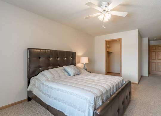 A bedroom with a bed, a ceiling fan, and a lamp.