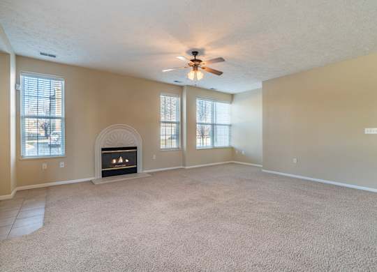A large living room with several windows, a fireplace, and a ceiling fan.