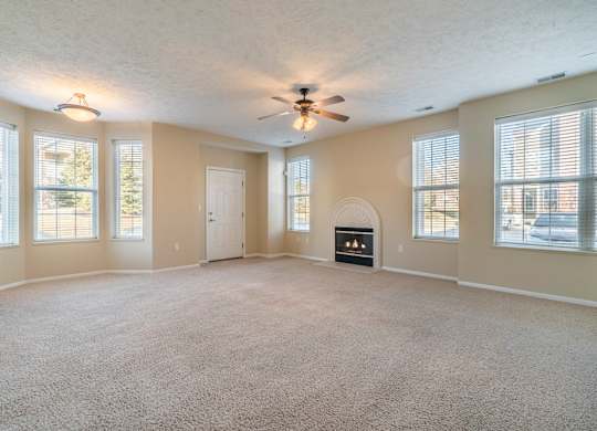A large living room with several windows, a fireplace, and a ceiling fan.