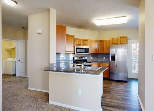 a kitchen featuring wooden cabinets, granite countertops, a peninsula, a tile backsplash, hardwood floors, and stainless steel appliances