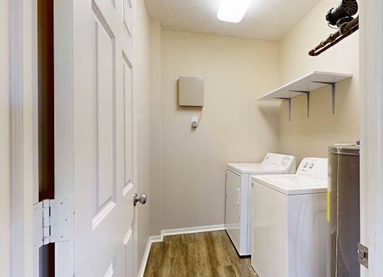 a laundry room with a full-sized washer and dryer with overhead shelving