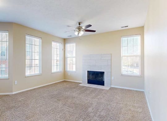 a large living room featuring multiple windows, a modern tiled fireplace, and carpeted flooring
