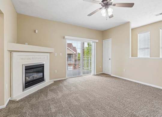 Carpeted apartment living room with fireplace, ceiling fan, sliding glass doors, and private balcony access.