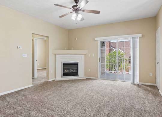 Apartment living room with carpet, fireplace, ceiling fan, and sliding glass doors leading to a balcony.