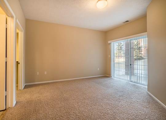 A room with carpeted floor and sliding glass doors.