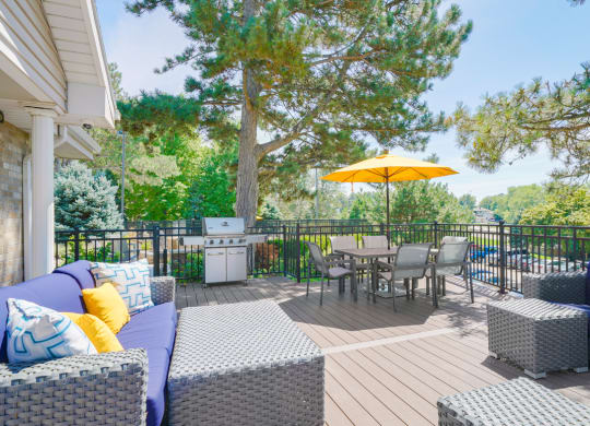 Sun deck with outdoor furniture and table and chairs shaded by a yellow umbrella