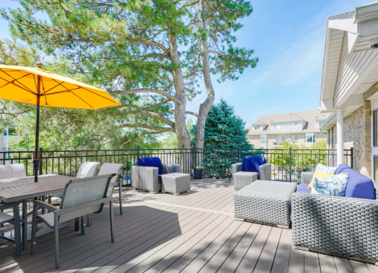 Sun deck with outdoor furniture and table and chairs shaded by a yellow umbrella