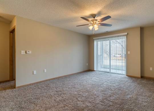 A room with a ceiling fan and carpeted floor.