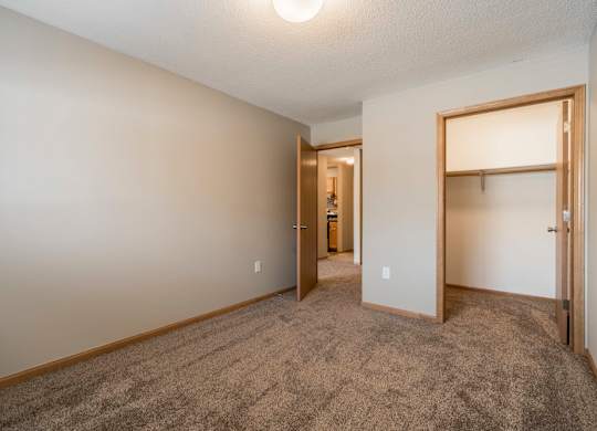 A room with a carpeted floor and a doorway leading to another room.