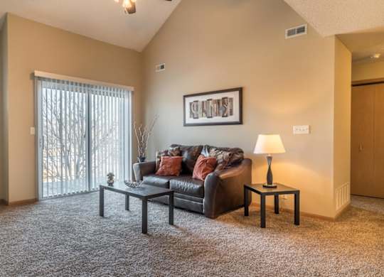 A living room with a grey couch, a small table with a lamp, and a framed picture on the wall.