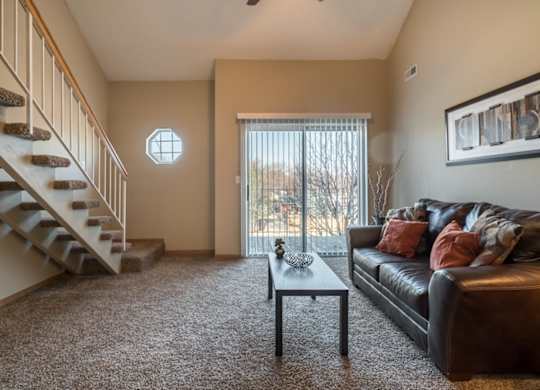 A living room with a couch, coffee table, and staircase.