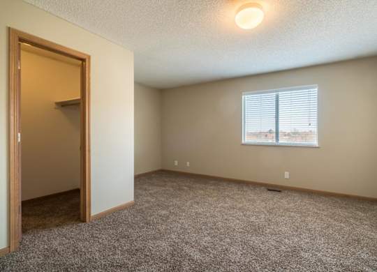 A room with a carpeted floor and a window with blinds.