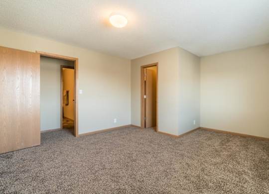 A room with carpeted floor and two doors.
