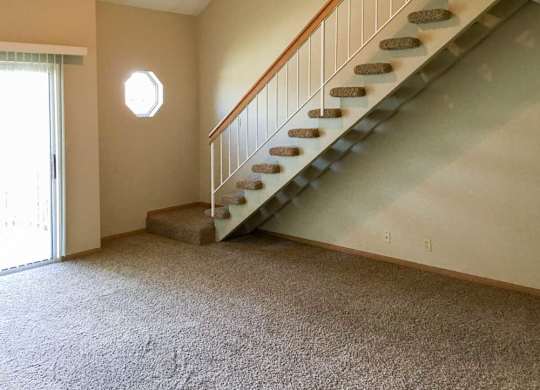 a living room with a staircase leading up to the loft