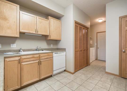 A kitchen with wooden cabinets and a white dishwasher.