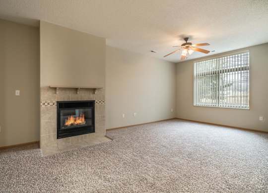 A living room with a fireplace and a ceiling fan.
