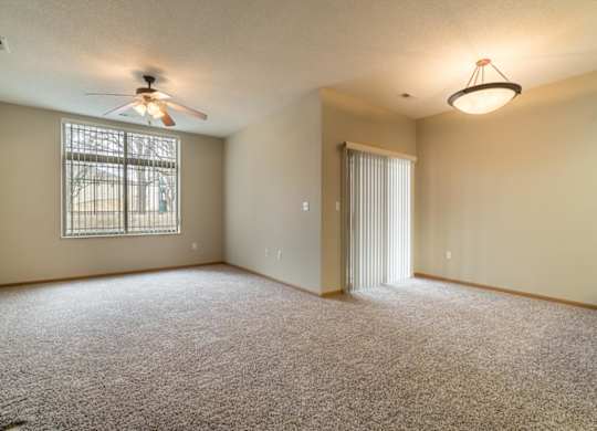 A room with a ceiling fan and carpeted floor.