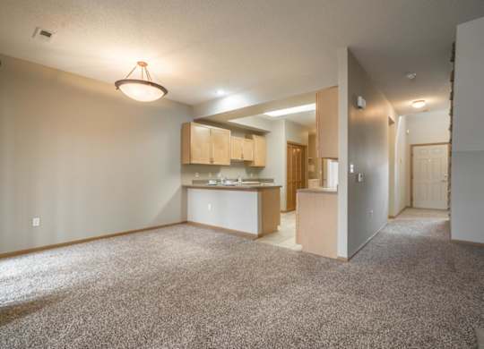 A spacious living room with a kitchenette in the background.