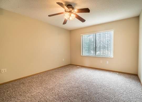 A room with a ceiling fan and a window with blinds.