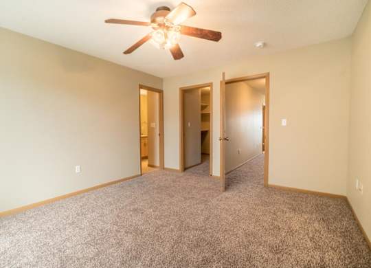 A room with a ceiling fan and carpeted floor.