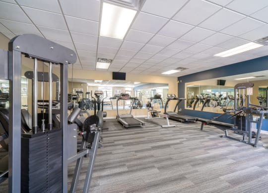 Bright and spacious exercise room featuring cardio machines, free weights, and weightlifting machines at Southwind Villas in LaVista NE 68128