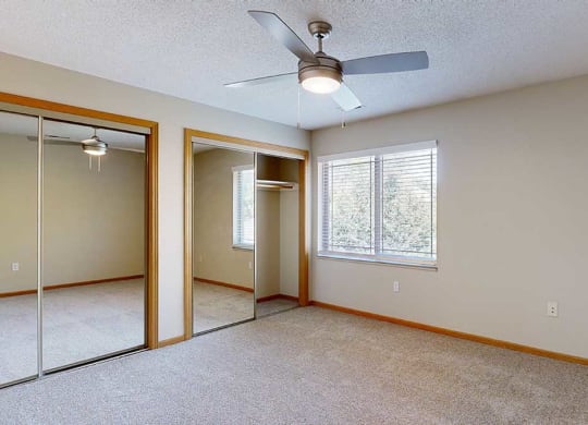 a bedroom with mirrored closet doors , a ceiling fan, and a large window