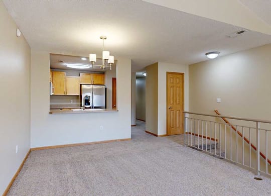 a living room next to a kitchen and staircase with a closet at the top