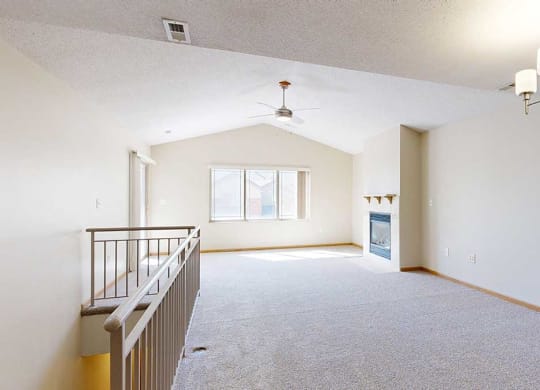 a living room next to a staircase that has a ceiling fan and fireplace