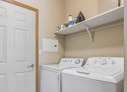 partment laundry room with full-size washer and dryer, shelving, and additional storage space.