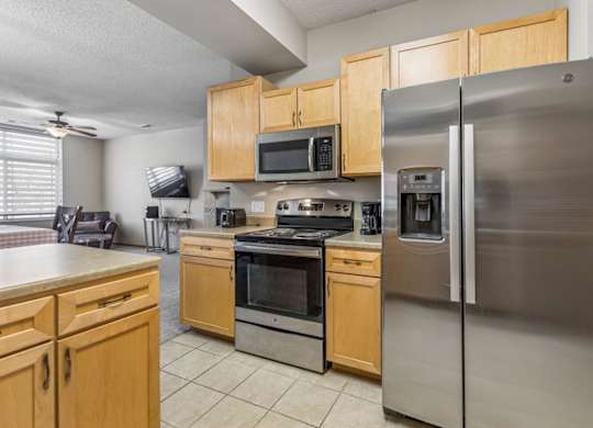 A kitchen with a stainless steel refrigerator and wooden cabinets.