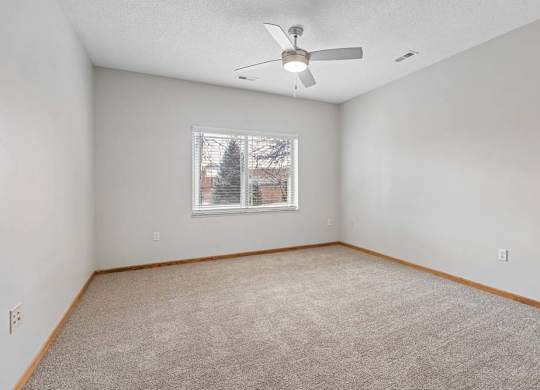 Carpeted bedroom with ceiling fan and window.