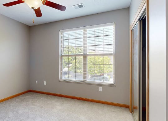 a bedroom with a large window, a ceiling fan, and a sliding door closet
