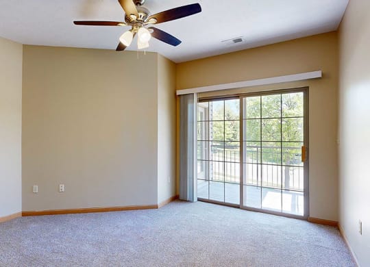 a bedroom with a ceiling fan and sliding glass door to a balcony