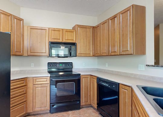 a kitchen with warm wooden cabinets and black appliances