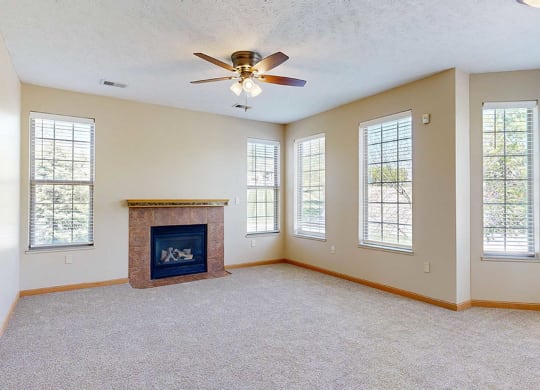 a living room with several windows, a fireplace, and a ceiling fan