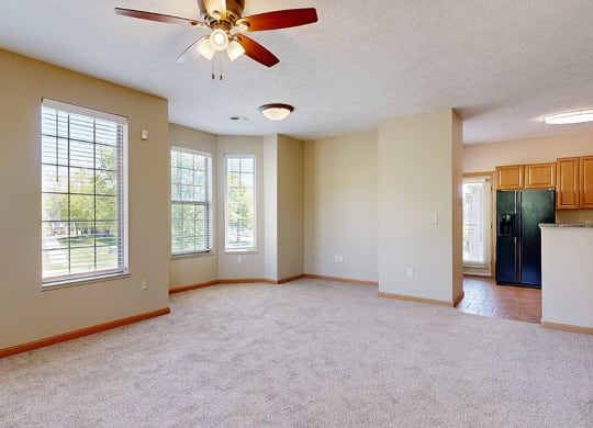 a living room with a ceiling fan adjacent to a dining space and kitchen