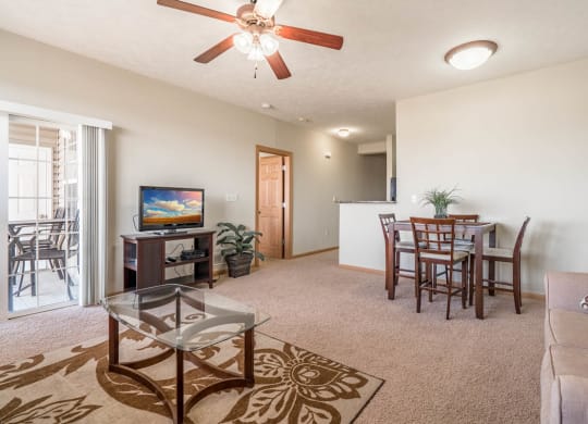 a living room and dining room with a table and a ceiling fan