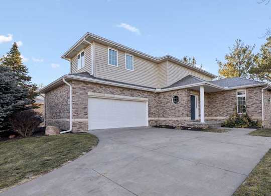 Front duplex exterior with brick facade, attached two-car garage, covered entry, and concrete driveway.