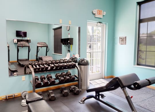 24 hour fitness center with cardio equipment and a large mirror