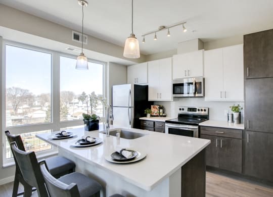 View of kitchen with white and dark contemporary cabinets and quartz countertops at The Central apartments near downtown Minneapolis MN 55408