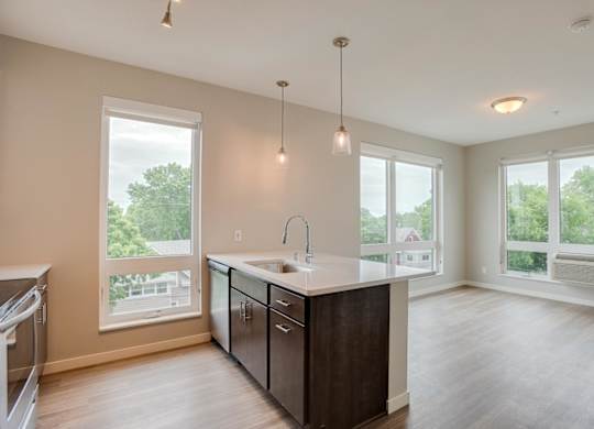 A kitchen with a large island and pendant lights.