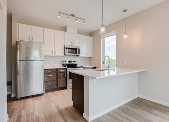 A kitchen with a refrigerator, microwave, and oven.