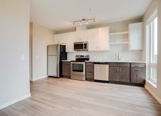 A kitchen with a refrigerator, microwave, oven, and cabinets.