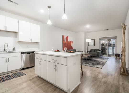Contemporary design scheme with white kitchen cabinetry, quartz countertops and open layout at The Conrad