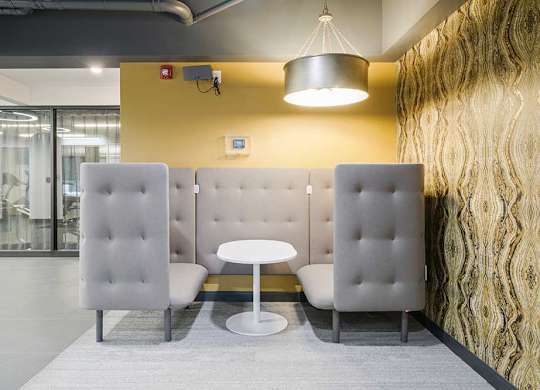 a modern cushioned booth with a  central table and walls for privacy