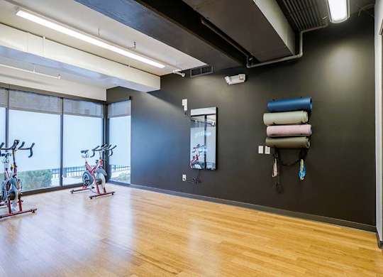 a yoga and spin studio with wooden floors and large windows