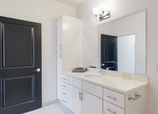 Furnished apartment bathroom with large white vanity and left side storage cabinet