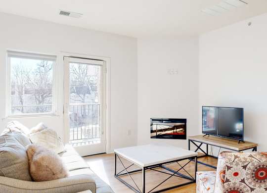 A living room with a couch, a coffee table, fireplace, and a television.